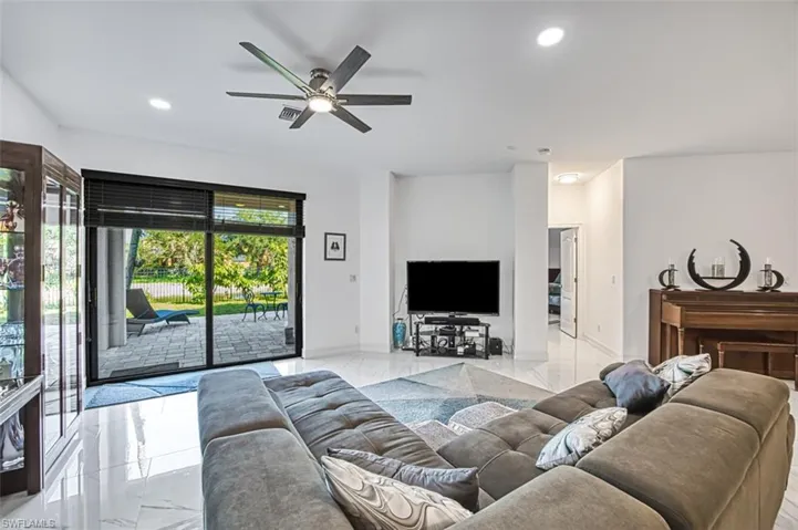Living room with ceiling fan, a healthy amount of sunlight, and light tile flooring