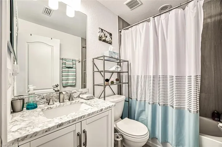 Full bathroom featuring shower / bath combo, large vanity, and toilet