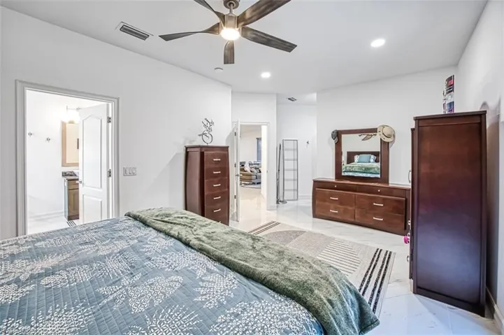 Tiled bedroom featuring ceiling fan and ensuite bath
