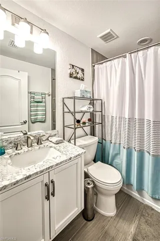 Bathroom featuring a textured ceiling, vanity, and toilet