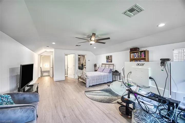 Bedroom with ceiling fan, lofted ceiling, and light wood-type flooring