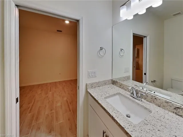 photo is of a previously completed home  Bathroom featuring vanity, wood-type flooring, and toilet