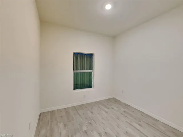 photo is of a previously completed home  Unfurnished room featuring light wood-type flooring