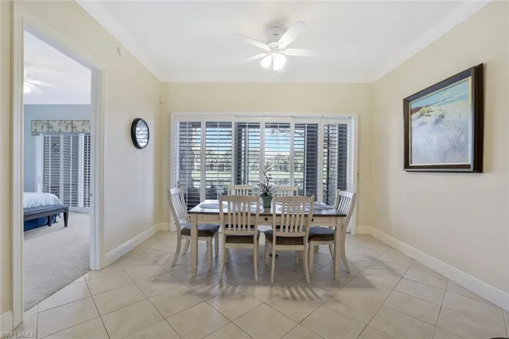 Dining space featuring a ceiling fan, ornamental molding, light tile patterned floors, and light carpet