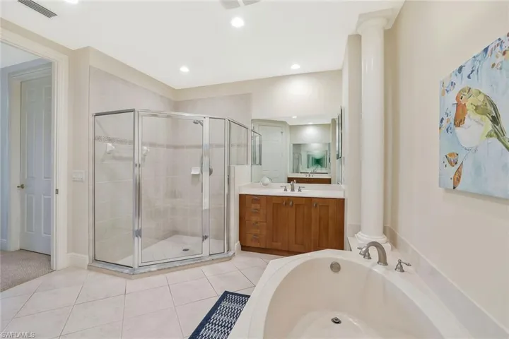 Full bath featuring vanity, a shower stall, a garden tub, tile patterned floors, and ornate columns