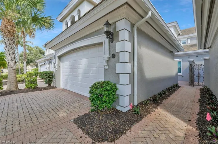 View of side of property with stucco siding, decorative driveway, and a garage