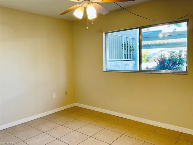 Tiled spare room featuring ceiling fan and a healthy amount of sunlight
