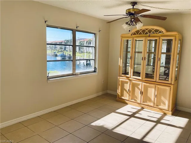 Tiled dinningroom with ceiling fan, a water view, and a textured ceiling