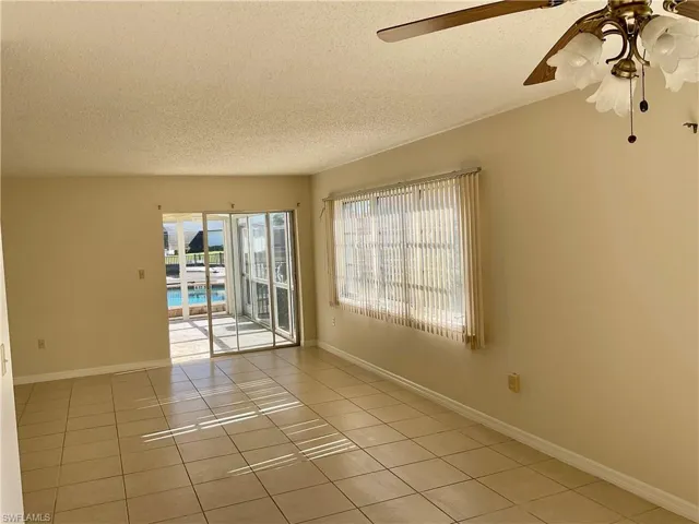 featuring ceiling fan, light tile patterned flooring, and a textured ceiling