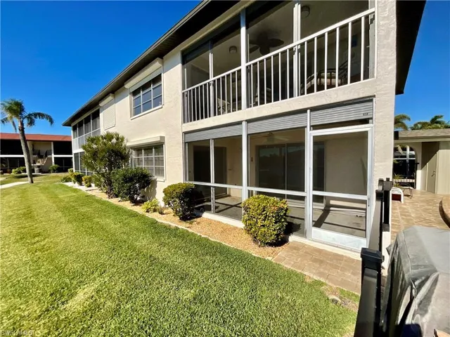 Rear view of property with ceiling fan and a lawn