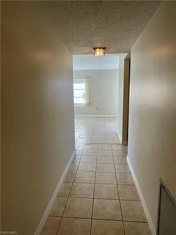 Hall featuring light tile patterned floors and a textured ceiling