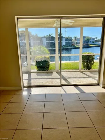 Doorway with tile patterned floors, a water view, and a healthy amount of sunlight
