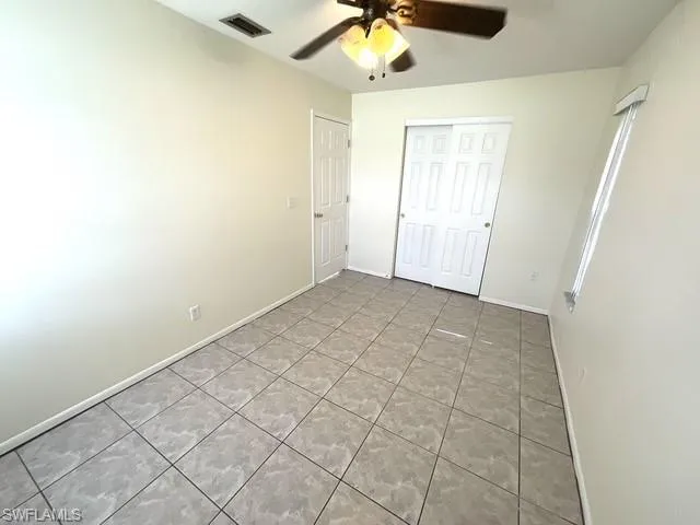 Unfurnished bedroom with light tile patterned floors, ceiling fan, and a closet