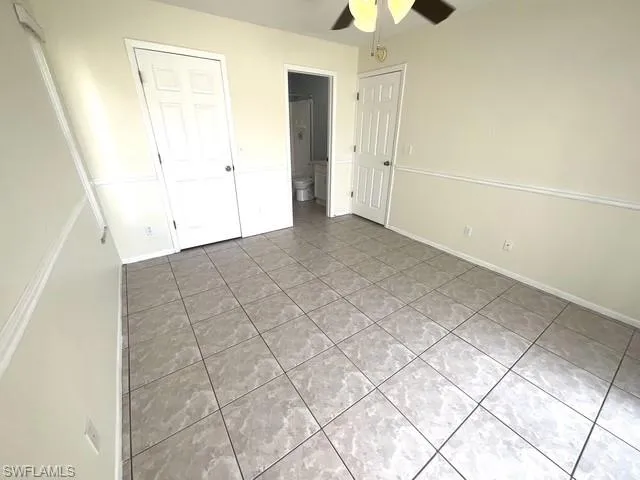 Unfurnished bedroom featuring light tile patterned floors, ceiling fan, a closet, and ensuite bathroom