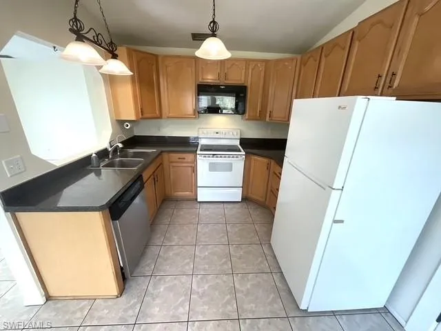 Kitchen with white appliances, dark countertops, and decorative light fixtures