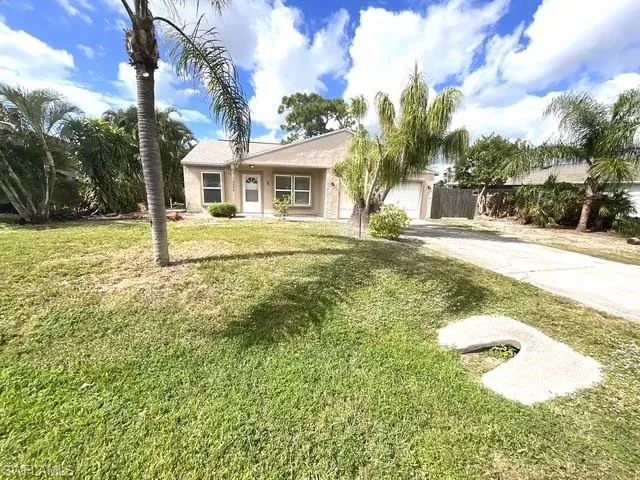 Single story home with a front yard, driveway, stucco siding, and a garage