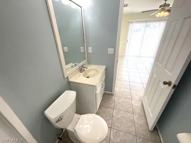Half bathroom with vanity, light tile patterned floors, and a ceiling fan