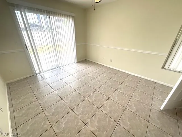 Empty room with light tile patterned floors and a ceiling fan