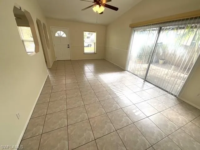 Foyer entrance with light tile patterned floors, healthy amount of natural light, vaulted ceiling, and ceiling fan