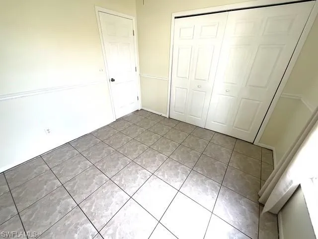 Unfurnished bedroom featuring light tile patterned floors and a closet
