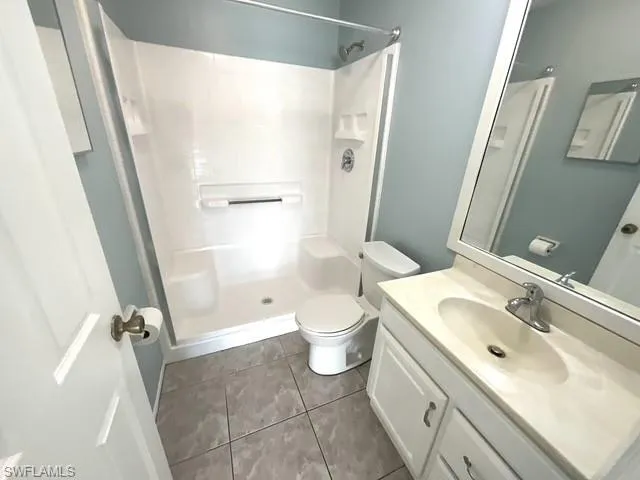 Bathroom featuring vanity, dark tile patterned floors, and a stall shower