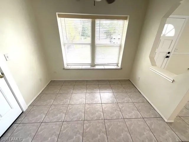 Foyer with arched walkways, light tile patterned floors, and a ceiling fan