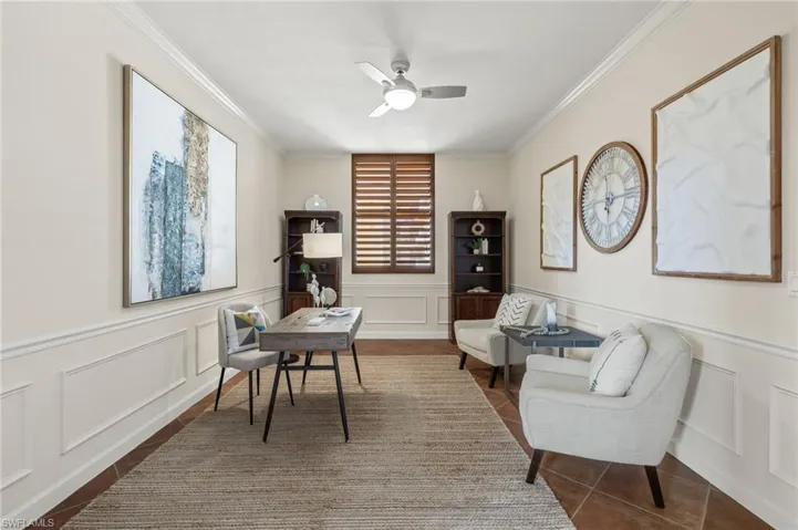 Office area with dark tile patterned floors, ceiling fan, and crown molding