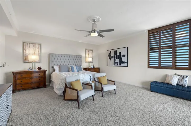 Carpeted bedroom featuring ceiling fan and ornamental molding