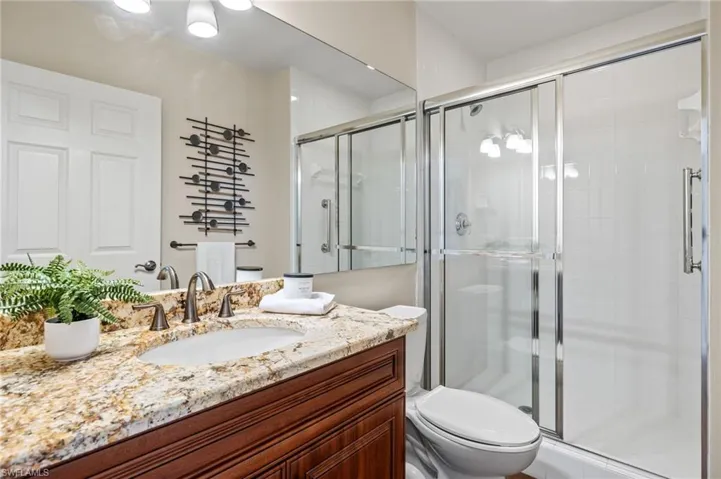 Bathroom with toilet, vanity, and an enclosed shower