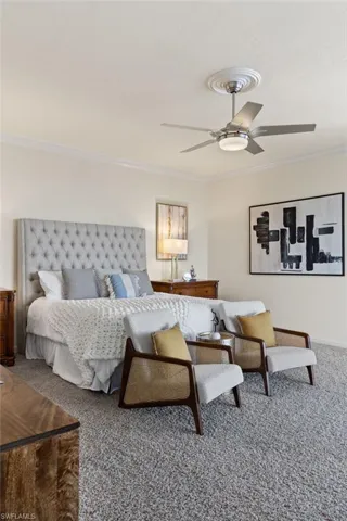 Carpeted bedroom featuring ornamental molding and ceiling fan