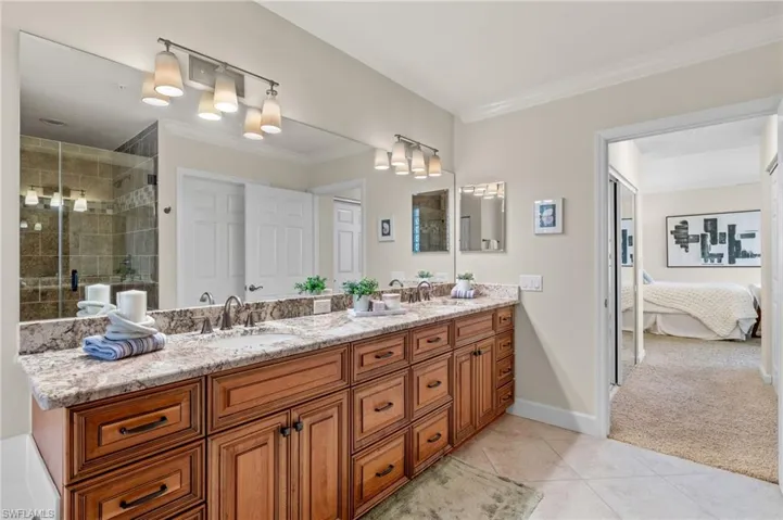 Bathroom featuring dual vanity, tile patterned floors, and a shower with door