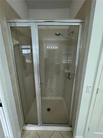 Bathroom featuring tile patterned floors and a shower with shower door