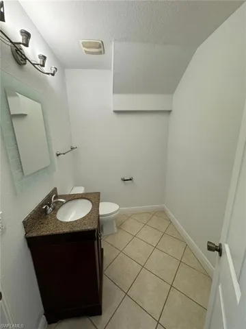 Bathroom with lofted ceiling, vanity, a textured ceiling, and tile patterned flooring