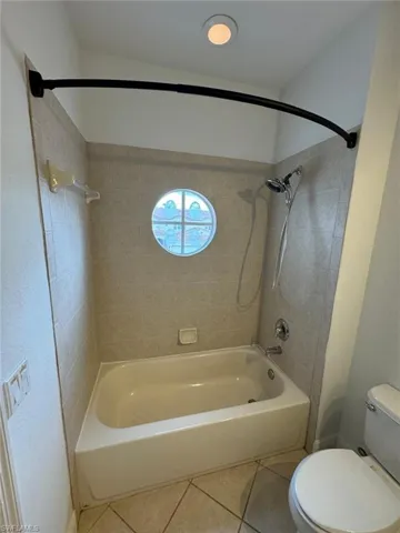 Bathroom with toilet, tiled shower / bath, and tile patterned floors