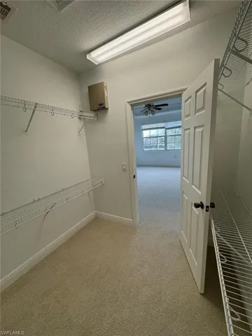 Spacious closet with ceiling fan and light colored carpet