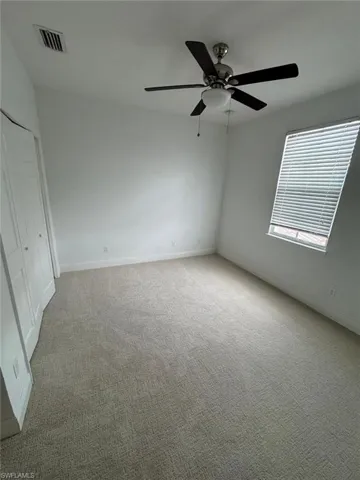 Unfurnished room featuring ceiling fan and light carpet