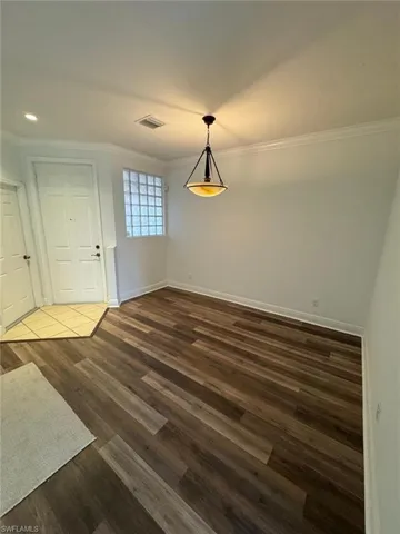 Unfurnished dining area with dark hardwood / wood-style flooring and crown molding