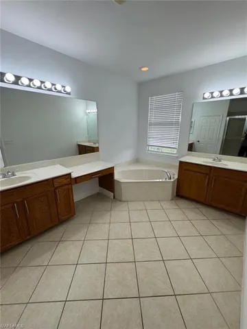 Bathroom featuring shower with separate bathtub, vanity, and tile patterned floors