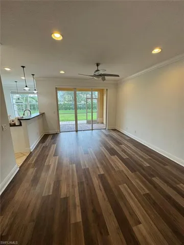 Unfurnished living room with ceiling fan, sink, dark hardwood / wood-style flooring, and ornamental molding