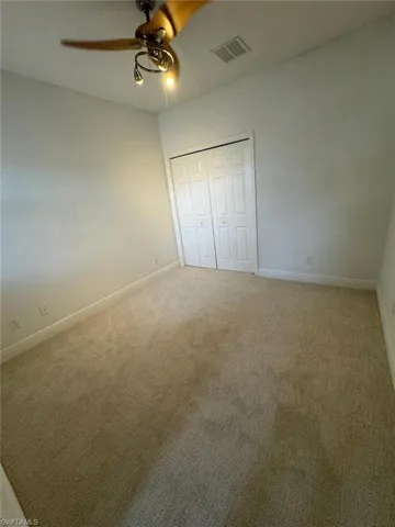 Unfurnished bedroom with ceiling fan, a closet, and carpet floors