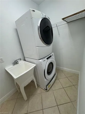 Clothes washing area featuring light tile patterned floors and stacked washer / dryer