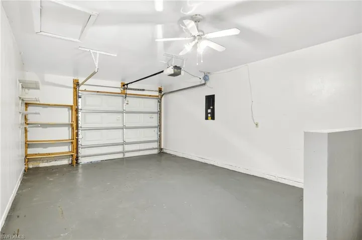 Garage featuring electric panel, a garage door opener, and ceiling fan
