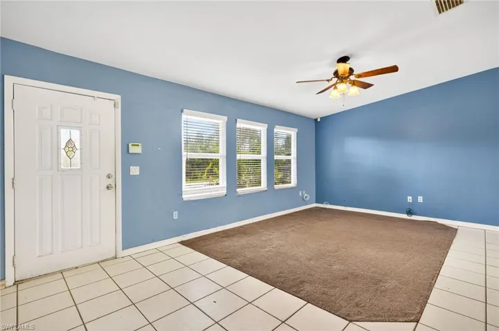 Foyer entrance with light tile patterned floors, ceiling fan, and light carpet