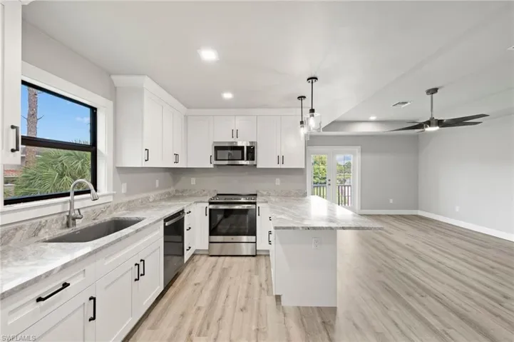 Kitchen featuring light   wood-style flooring, stainless steel appliances, sink, hanging light fixtures, and ceiling fan