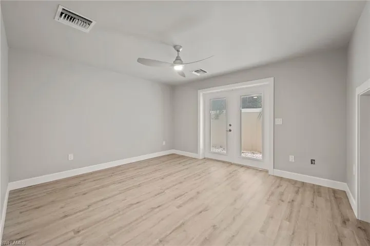 Empty room with french doors, light wood-type flooring, and ceiling fan