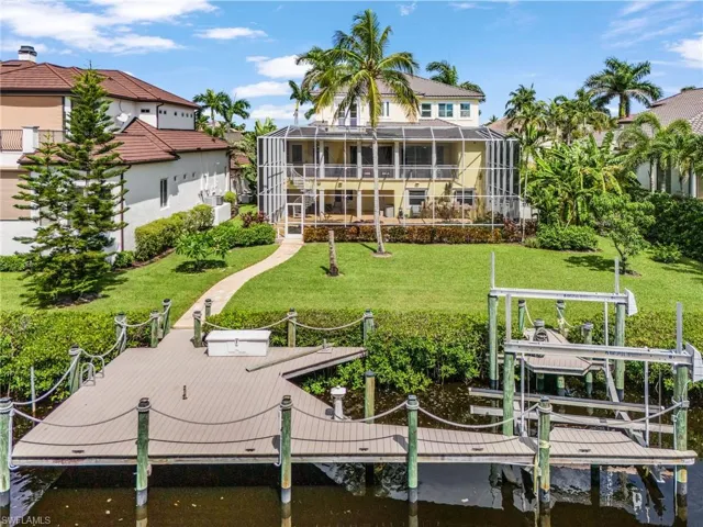 Rear view of house featuring boat lift, a yard, a sunroom, a lanai, and a water view