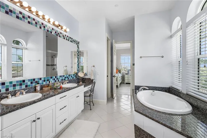 Bathroom featuring a shower stall, ensuite bath, double vanity, a bath, and light tile patterned floors