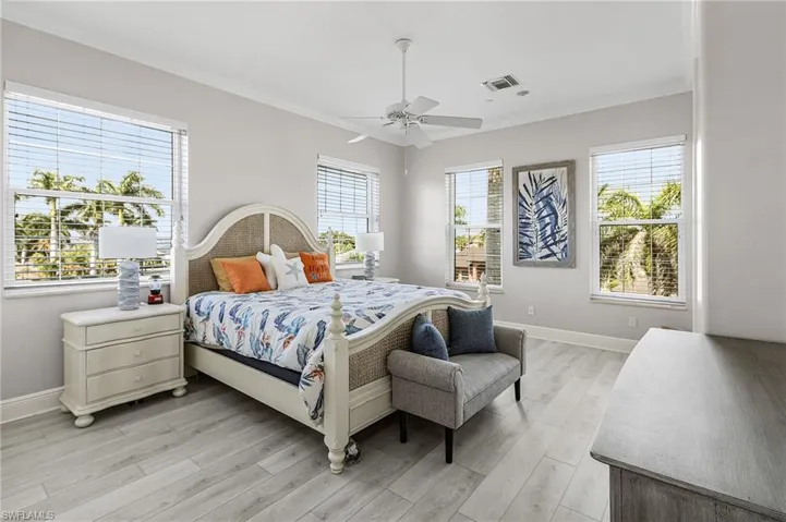 Bedroom featuring multiple windows, light wood finished floors, ornamental molding, and a ceiling fan