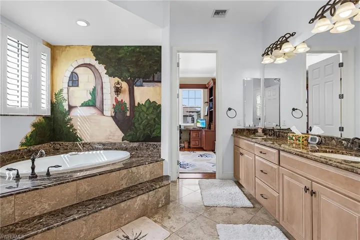 Bathroom featuring double vanity, a garden tub, healthy amount of natural light, light tile patterned floors, and recessed lighting