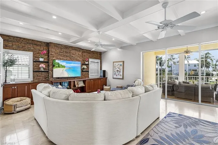 Living room with beam ceiling, plenty of natural light, light tile patterned floors, coffered ceiling, and recessed lighting